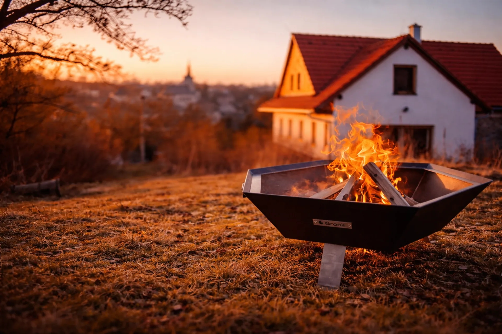 Ohniště GRANIL Hexagon Go s ohněm v zahradě při západu slunce